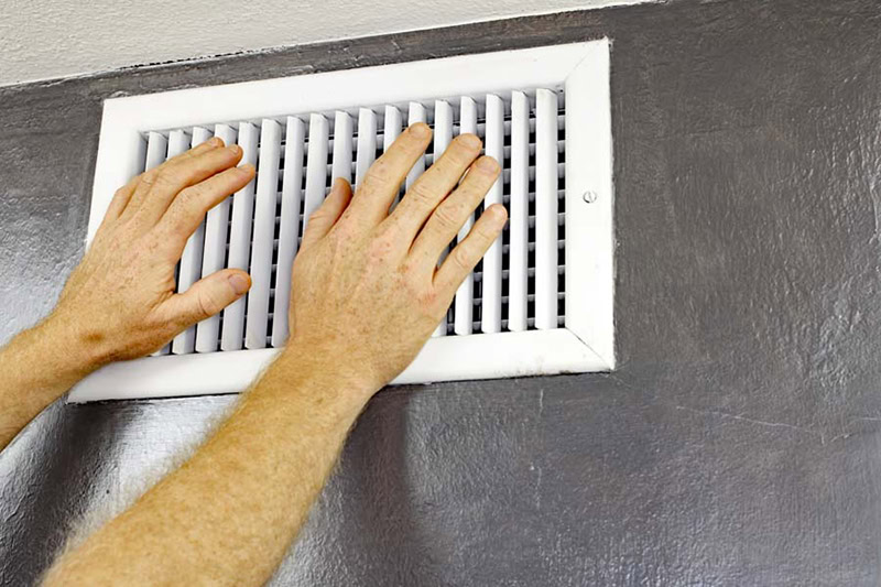 Blog Title: Why Is My AC Blowing Hot Air? Photo: Hands in front of the vent