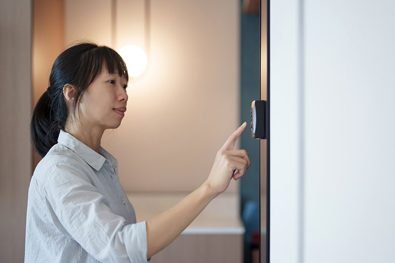 A young woman interacting with a digital interface or smart lock inside a modern home.